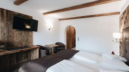 Gemütliches Hotelzimmer mit Holzakzenten, Doppelbett und Fernseher an der Wand