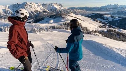Zwei Skifahrer blicken auf verschneite Berge bei klarem Himmel