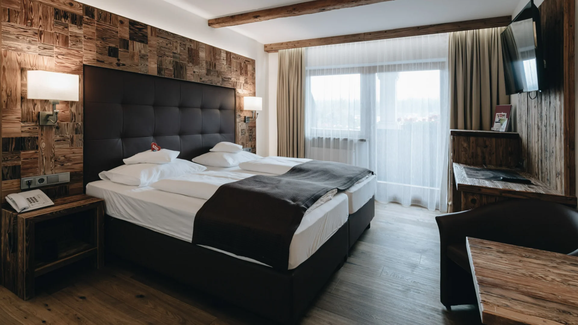 Modernes Schlafzimmer mit Doppelbett, Holzdecke und großem Fenster