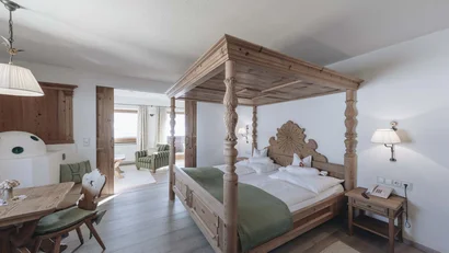 Gemütliches Hotelzimmer mit Holz-Himmelbett und Sitzbereich