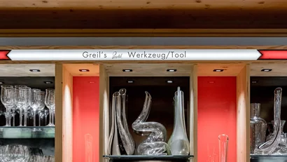 Vitrine mit Glasobjekten unter dem Schild Greils Werkzeug