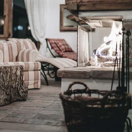 Gemütliches Wohnzimmer mit Kamin, karierten Sesseln und Baumstamm-Tisch