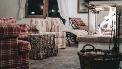 Gemütliches Wohnzimmer mit Kamin, karierten Sesseln und Baumstamm-Tisch