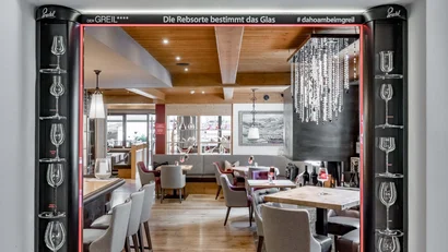 Blick durch eine Tür mit Weingläsern auf gemütlichen Gastraum mit Tischen und Stühlen