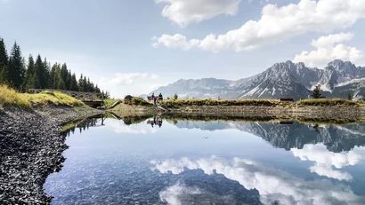 Spiegelung von Wolken, Bergen und Bäumen in klarem Bergsee