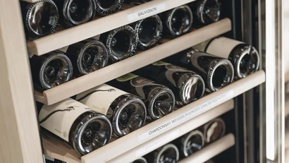 Weinflaschen in Holzregalen eines Weinkühlschranks