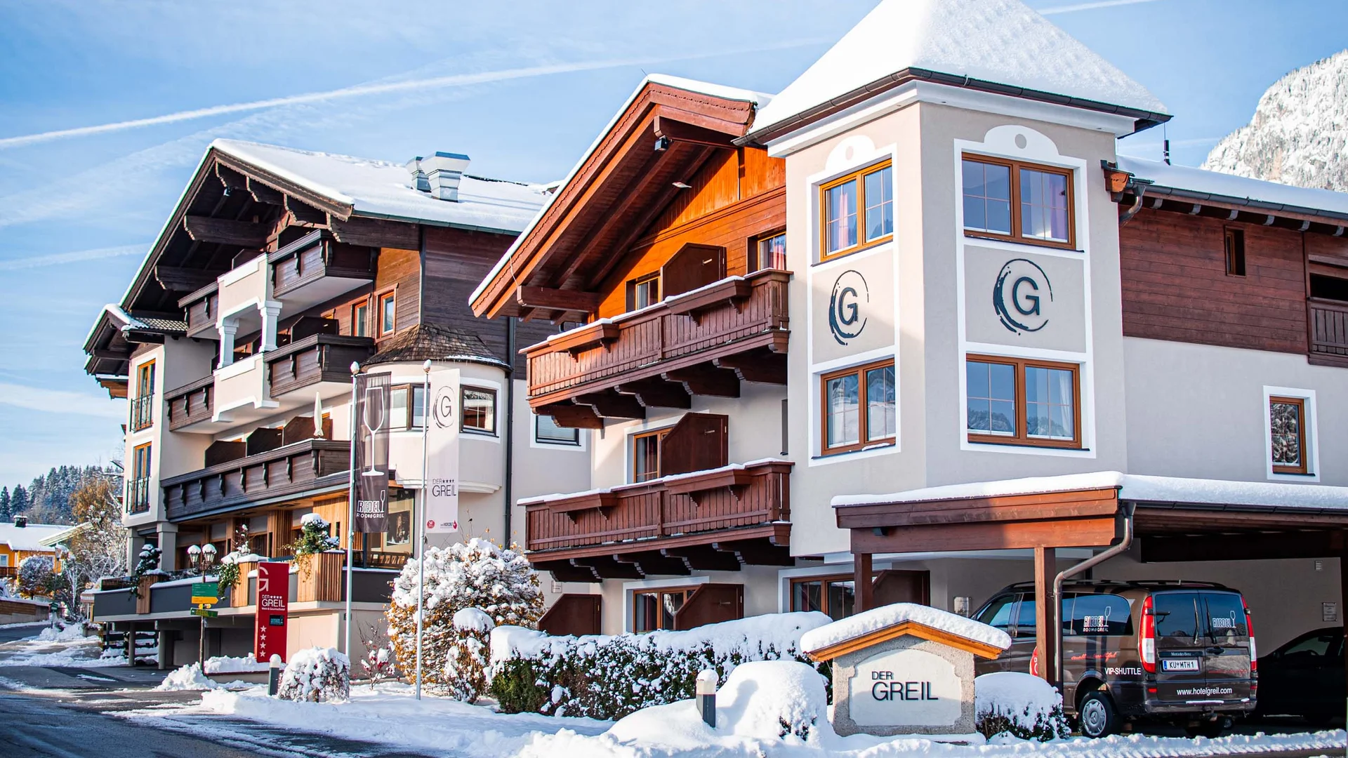 Hotel Der Greil im Winter mit verschneitem Dach und Bergkulisse