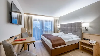 Modernes Hotelzimmer mit einem Doppelbett, Tisch, Stühlen und Balkon